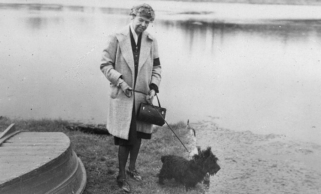 Eleanor Roosevelt walking a dog by a lake