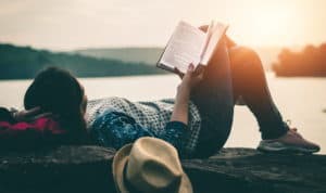 Woman reading in front of a lake